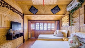 Une pièce de style cabane en bois, avec deux lits, une télévision et une fenêtre agrémentée de volets décoratifs.