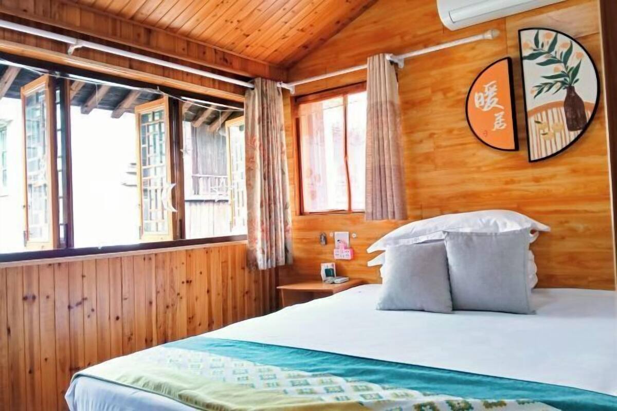 Una habitación de madera con una cama, un ventanal con cortinas y un diseño circular en la pared.