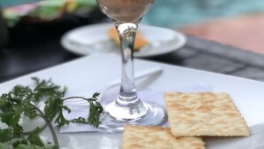 Ensalada de mariscos en un vaso, adornada con lechuga, tomate y una rodaja de naranja, acompañada de pan plano sobre una mesa junto a una piscina.