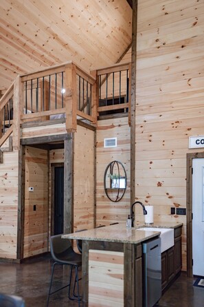 A wooden interior with a kitchen area, a dining space, and a staircase leading to an upper level.