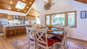 A spacious kitchen with wooden cabinets, a central island, and a dining area with a table and chairs. - 10 SHARC/basketball ct/ac/private hot tub+bikes +snow sleds (Sunriver)