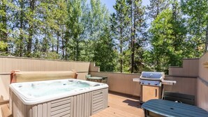 A wooden deck with a hot tub, a grill, and a table. - 10 SHARC/basketball ct/ac/private hot tub+bikes +snow sleds (Sunriver)