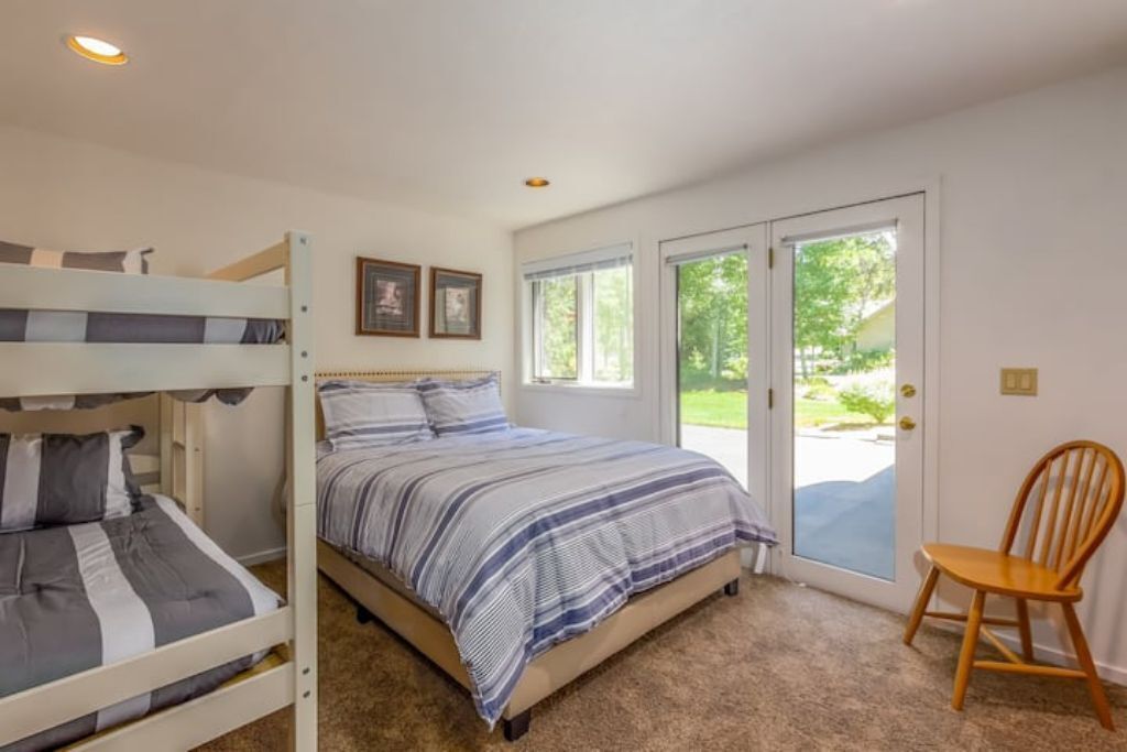 A bedroom with bunk beds, a single bed, a chair, and a door leading to a balcony.
