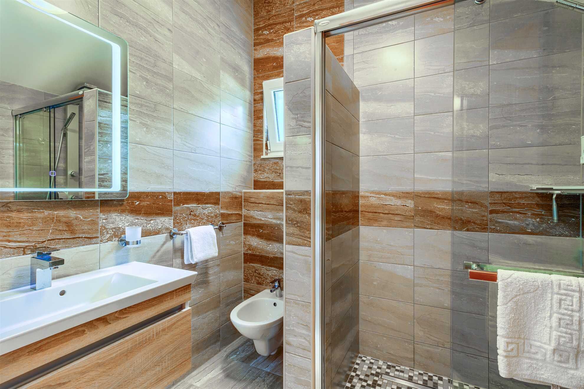 Une salle de bain moderne avec une douche à parois de verre, un lavabo et un bidet.