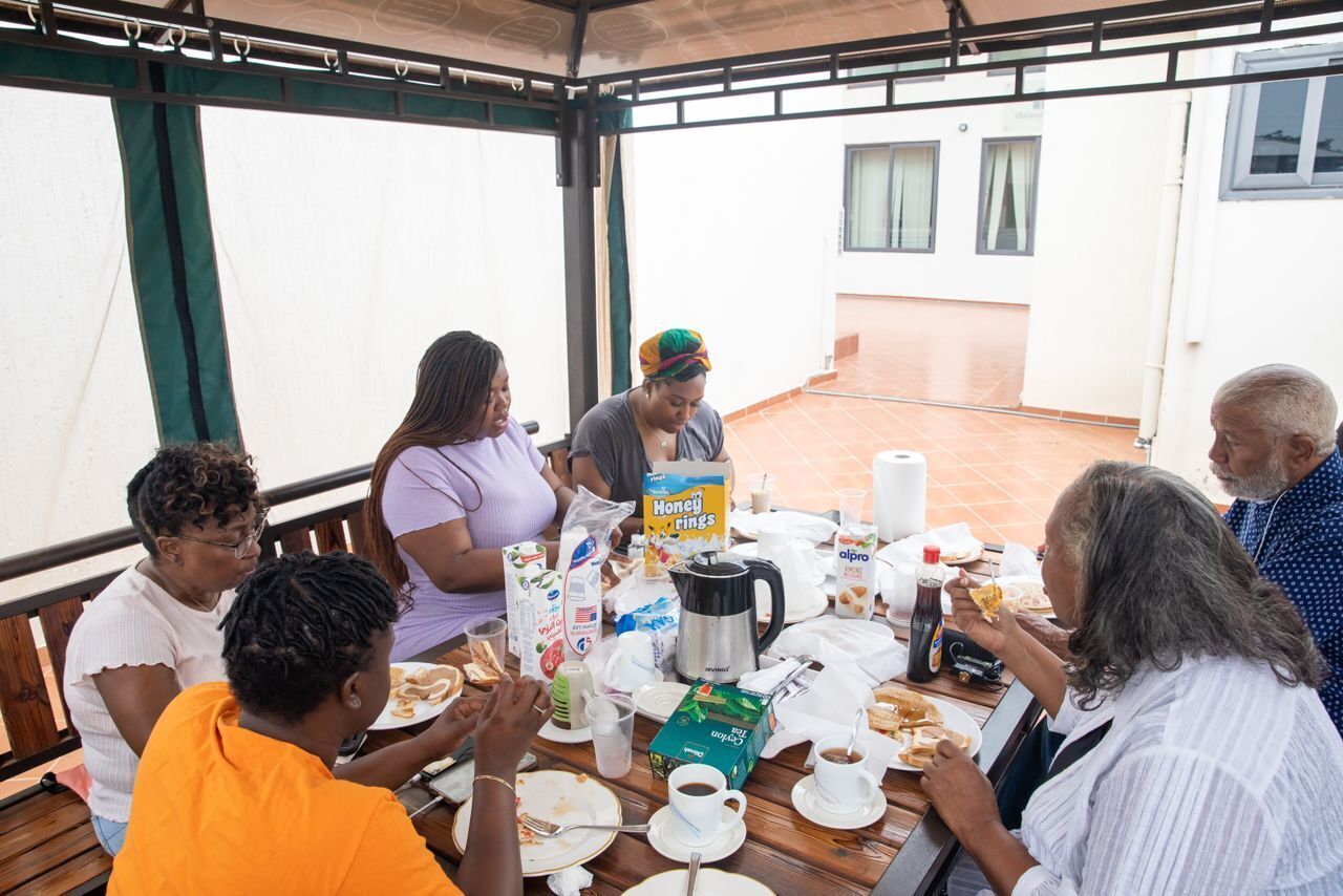 Un groupe de personnes est assis à une table en plein air et déguste divers plats et boissons.