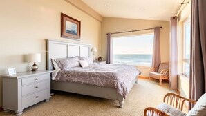 Ein Schlafzimmer mit Bett, Nachttisch, Stuhl und Meerblick.
