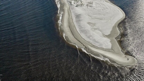 An aerial view of a coastal area with a beach, a marina, and residential buildings. - Sea La Vie (Ocean Isle Beach)
