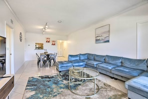 A living room with a sectional sofa, a glass coffee table, and a patterned rug.