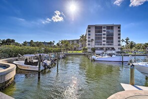 A marina with boats docked, a large building in the background, and a clear sky.