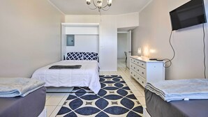 Ein Schlafzimmer mit einem Bett, einem Schminktisch, einem an der Wand befestigten Fernseher und einer Chandelieber.