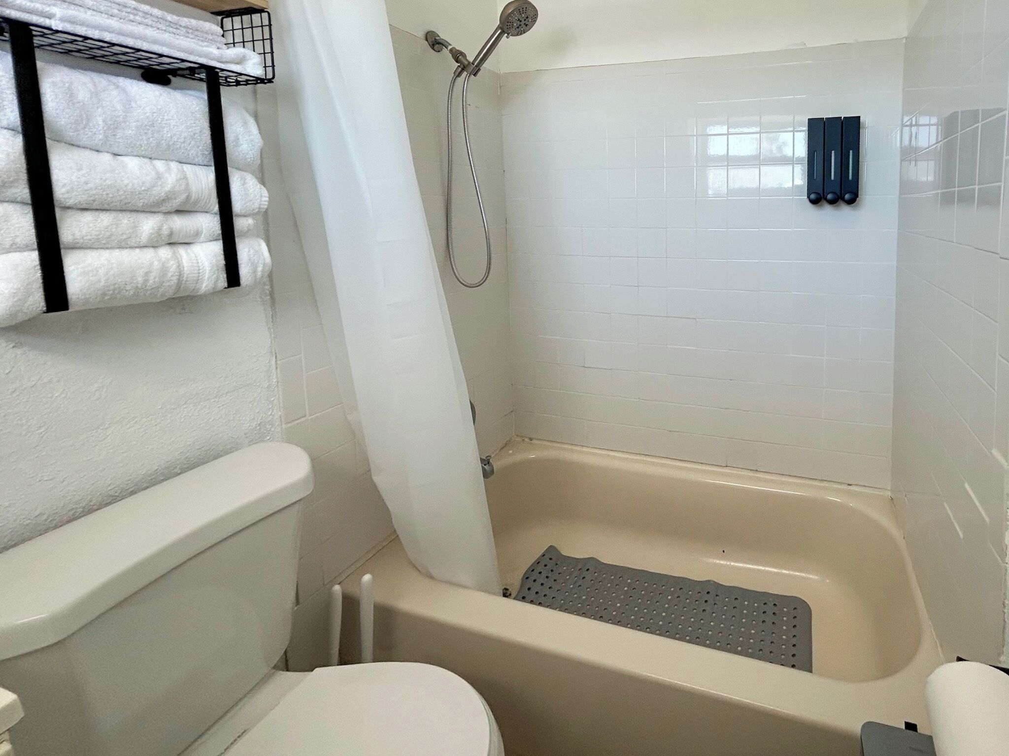Une salle de bain équipée d’une baignoire, de toilettes et d’un porte-serviettes avec des serviettes pliées.