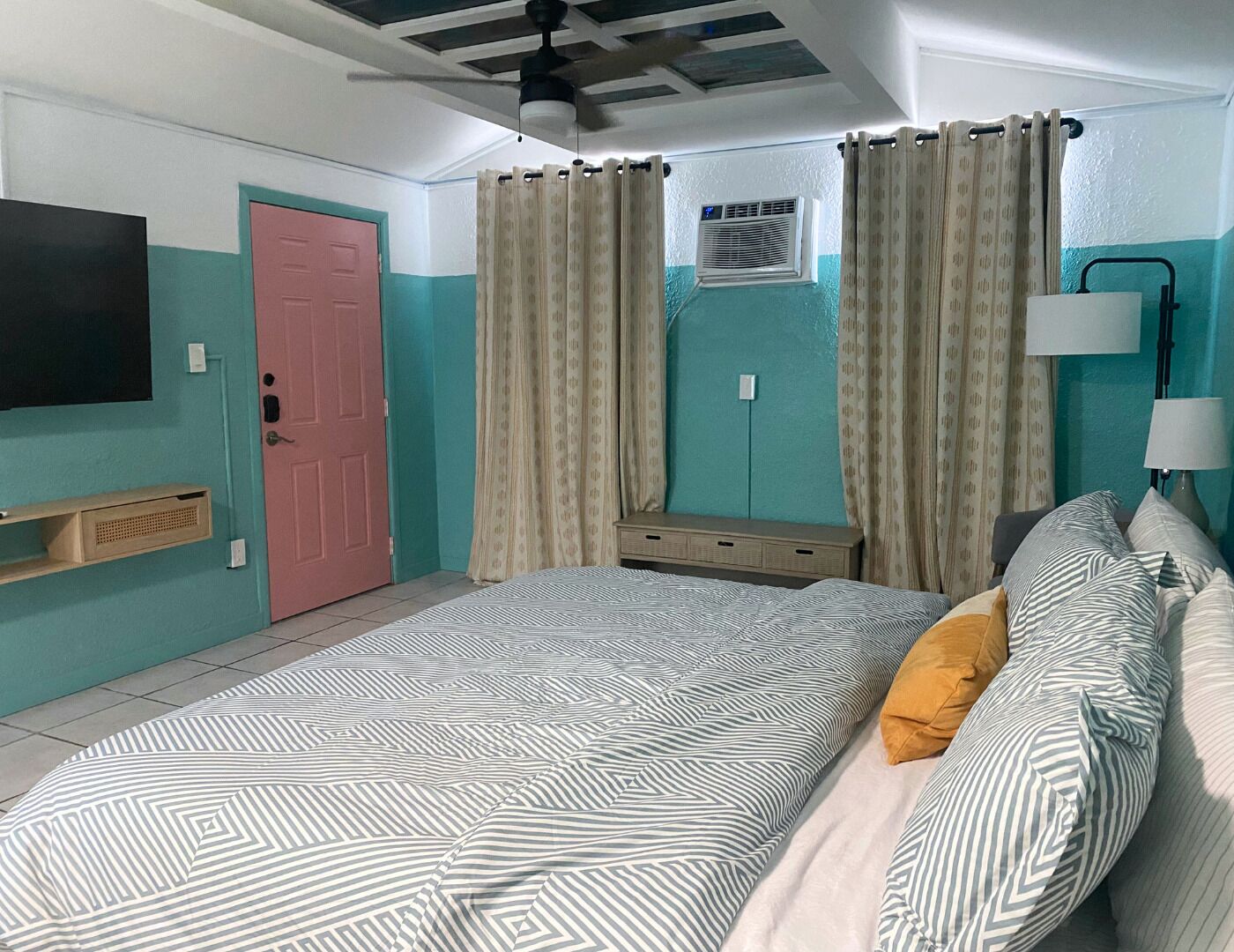 Une chambre à coucher comprenant un lit, une télévision, une armoire et un ventilateur de plafond.