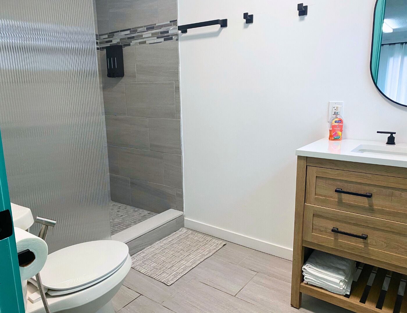 A modern bathroom with a toilet, shower, and sink.