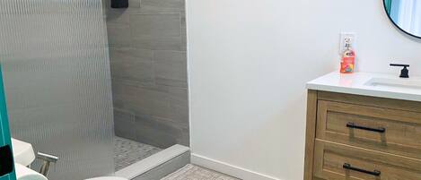 A modern bathroom with a toilet, shower, and sink.