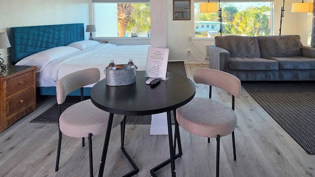 Een hotelkamer met een bed, een eettafel met stoelen, een bank en uitzicht op het landschap.