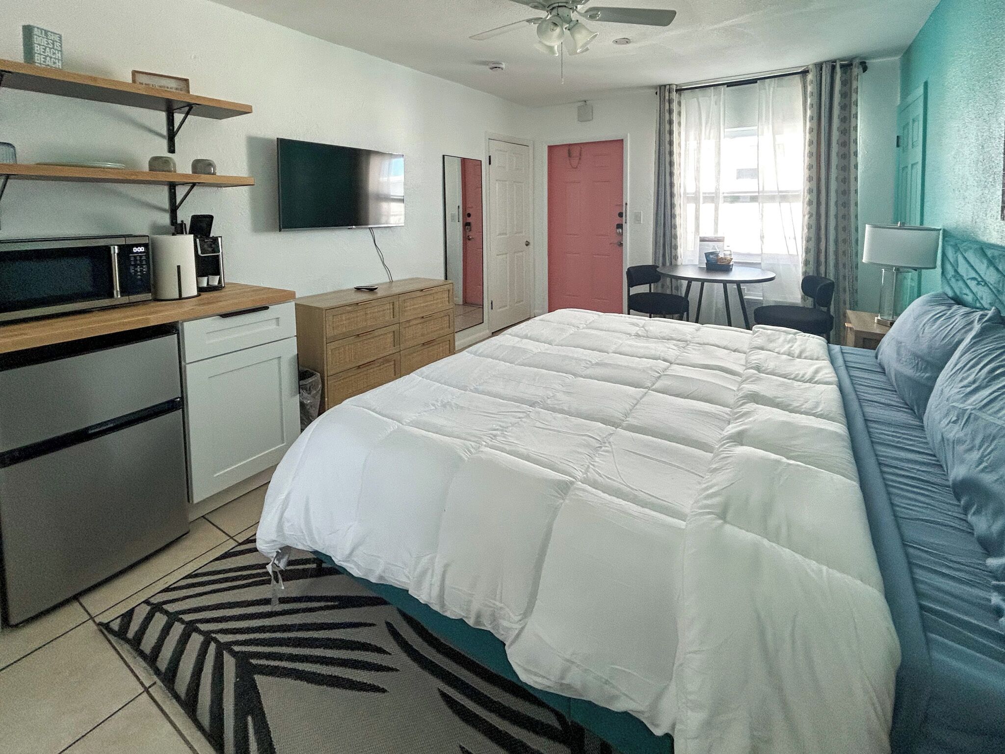 Un dormitorio con cama, escritorio, silla, televisor, microondas y cafetera.