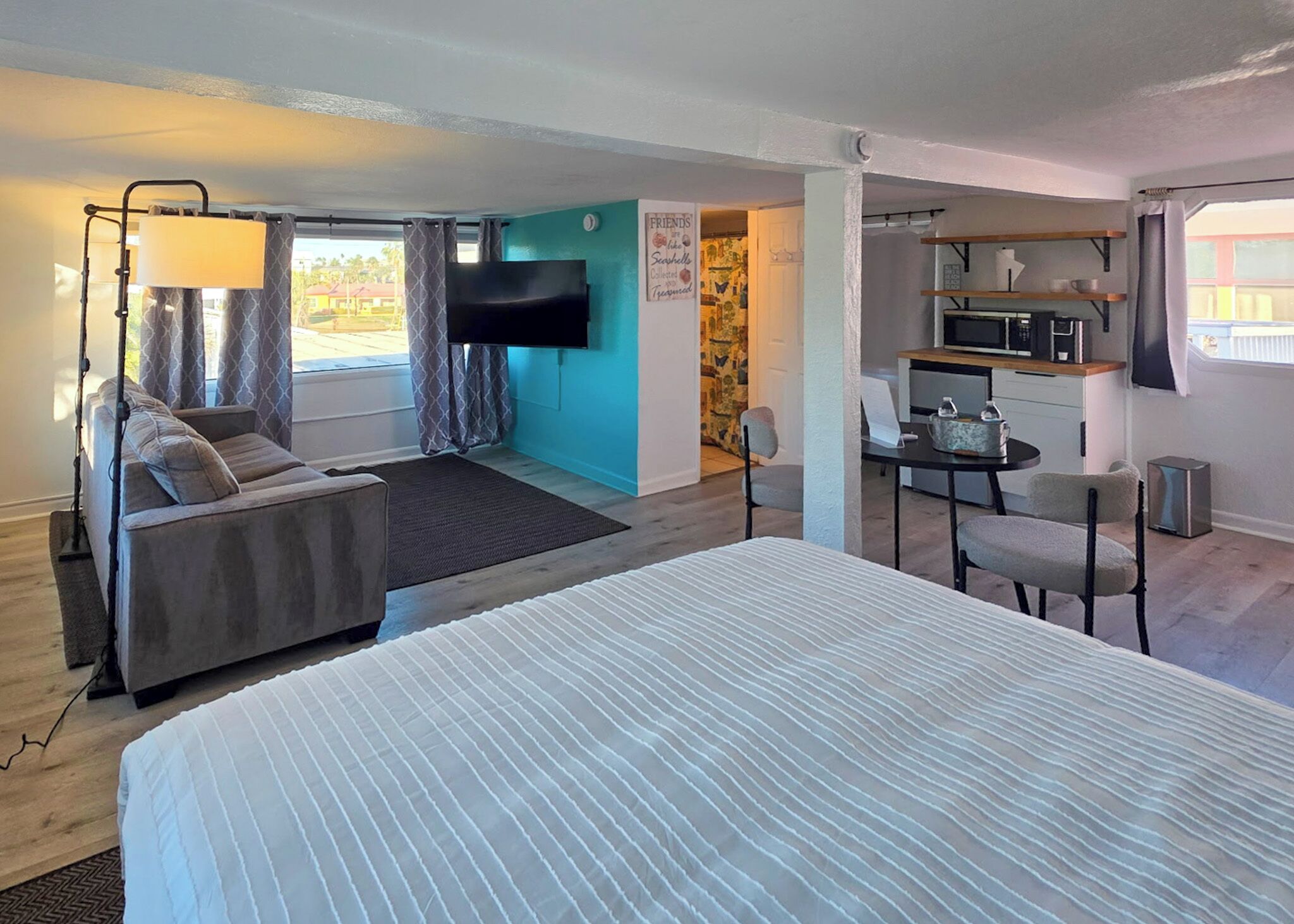 Una habitación de hotel con cama, sofá, escritorio, televisor y kitchenette.