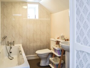 Een badkamer met een badkuip, toilet en een raam.