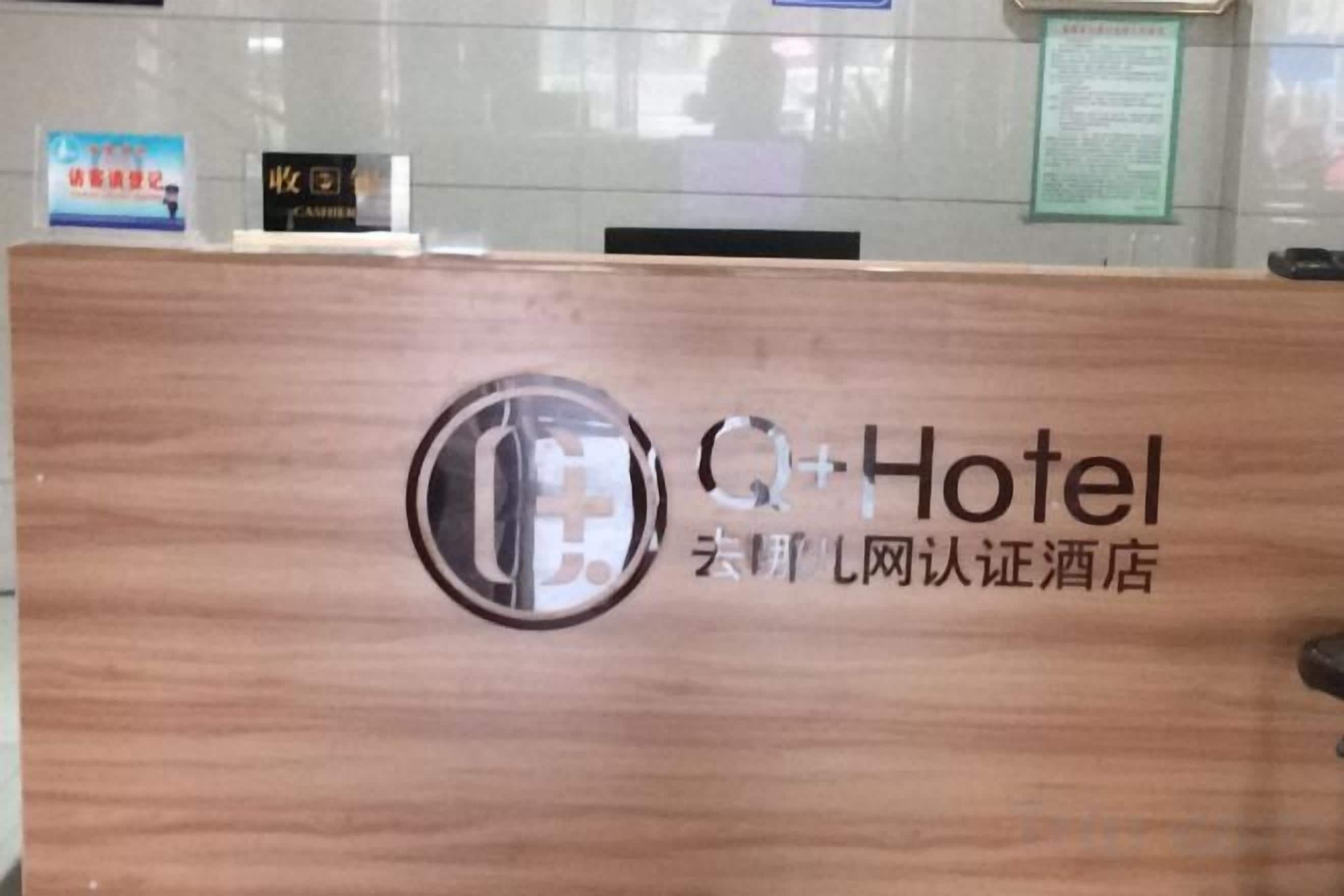 A reception desk with a logo and text indicating it is a Q+Hotel.