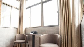 A corner room with two chairs, a small table, and a window with curtains. - Taohuanyuan Hotel (Zongyang)