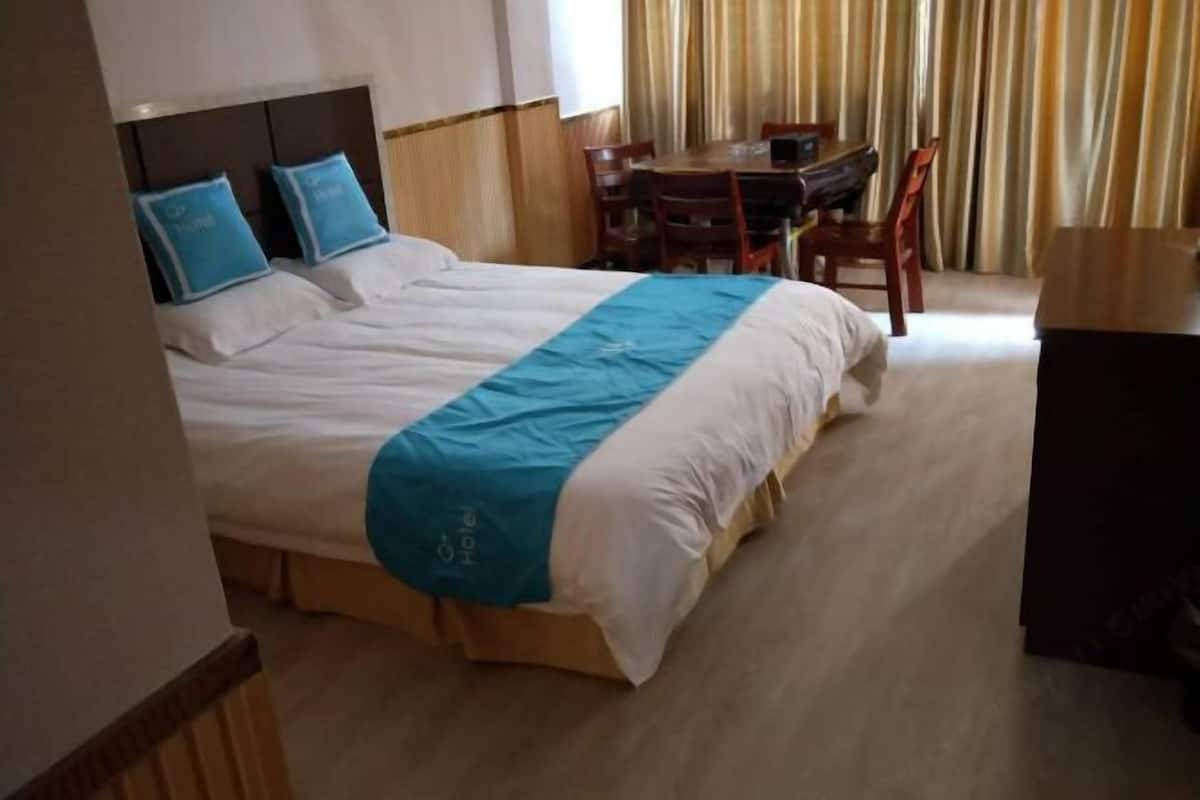 Et hotelværelse med en stor seng, et skrivebord og en stol.