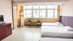 A hotel room with two beds, a desk with chairs, a TV, and a window with curtains. - Taohuanyuan Hotel (Zongyang)