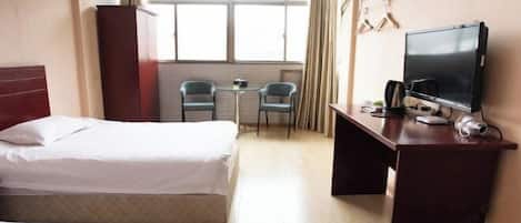 A hotel room with two beds, a desk with a TV, a small table, and chairs.