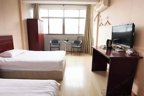 A hotel room with two beds, a desk with a TV, a small table, and chairs. - Taohuanyuan Hotel (Zongyang)
