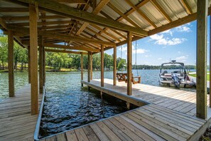 Une jetée en bois s’étendant au-dessus de l’eau, avec un espace de repos couvert et un bateau amarré à proximité.