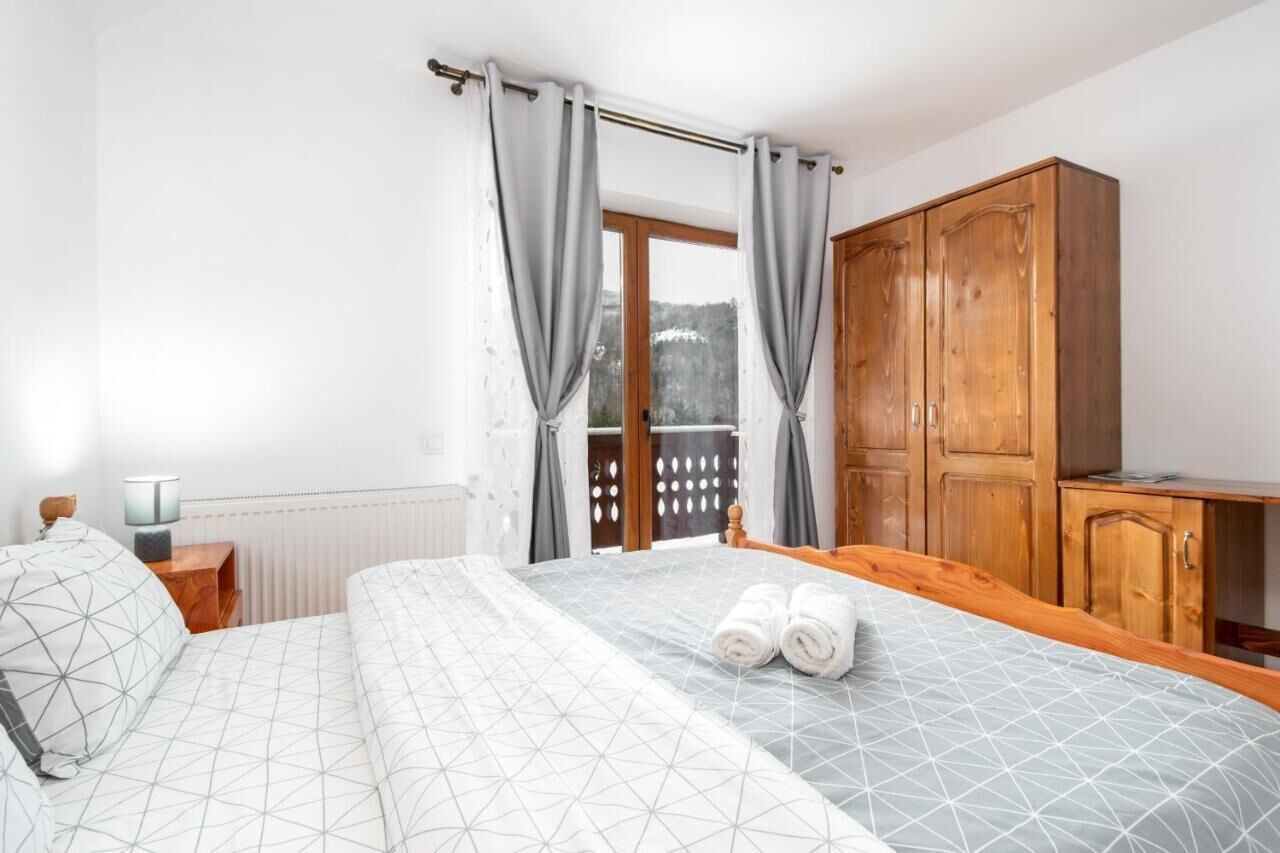 Ein Schlafzimmer mit einem Bett, einem Holzschrank und einem Fenster mit Vorhängen.