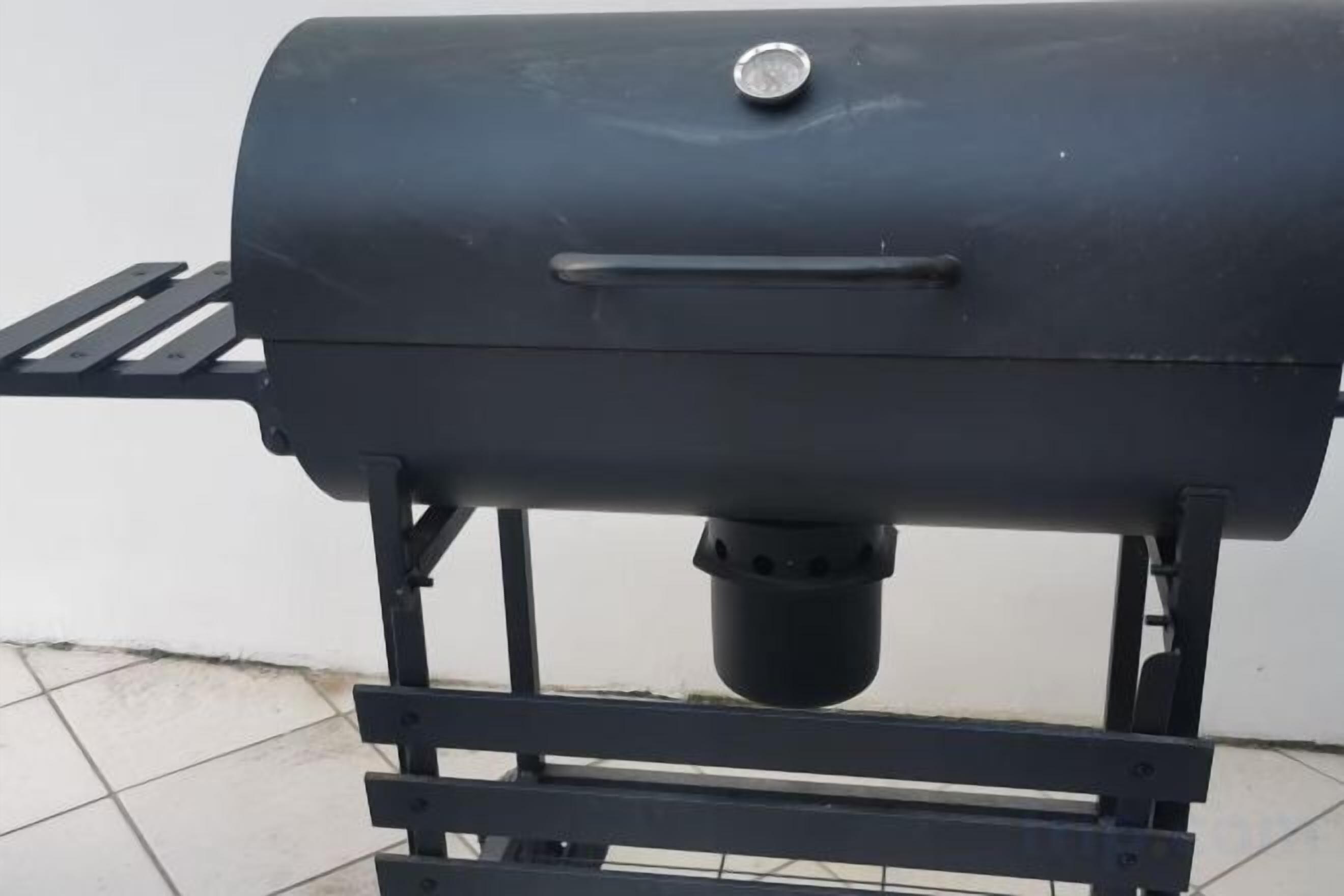 Ein schwarzer Grill mit Tragegriff und Lüftung, montiert auf einem Metallständer.