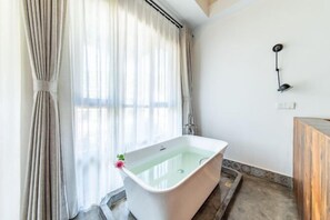Une salle de bain avec une baignoire sur pieds, une douche et un meuble-lavabo en bois.