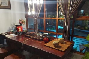 Un coin bar en bois avec une grande fenêtre, une bouilloire rouge et divers ensembles à thé.