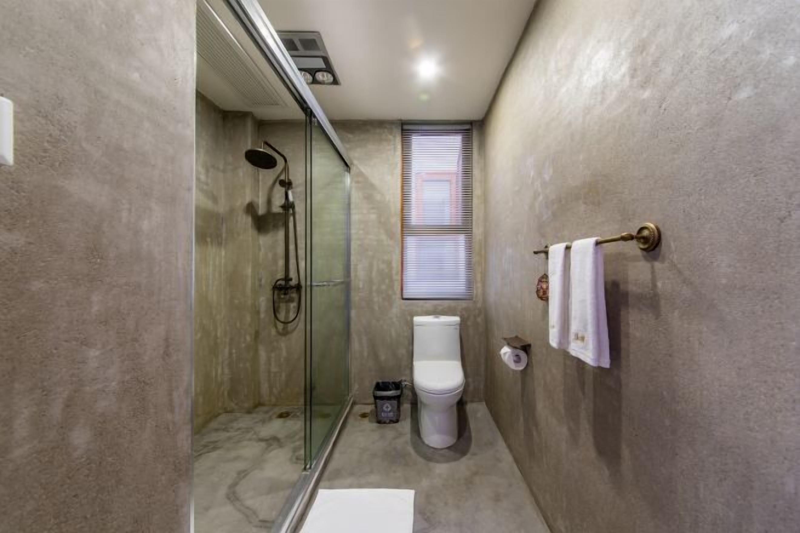 Un baño pequeño con cabina de ducha de vidrio, un inodoro y un perchero para toallas.