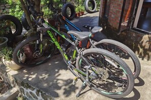 Un vélo appuyé contre un mur de briques, avec une clôture métallique en arrière-plan.