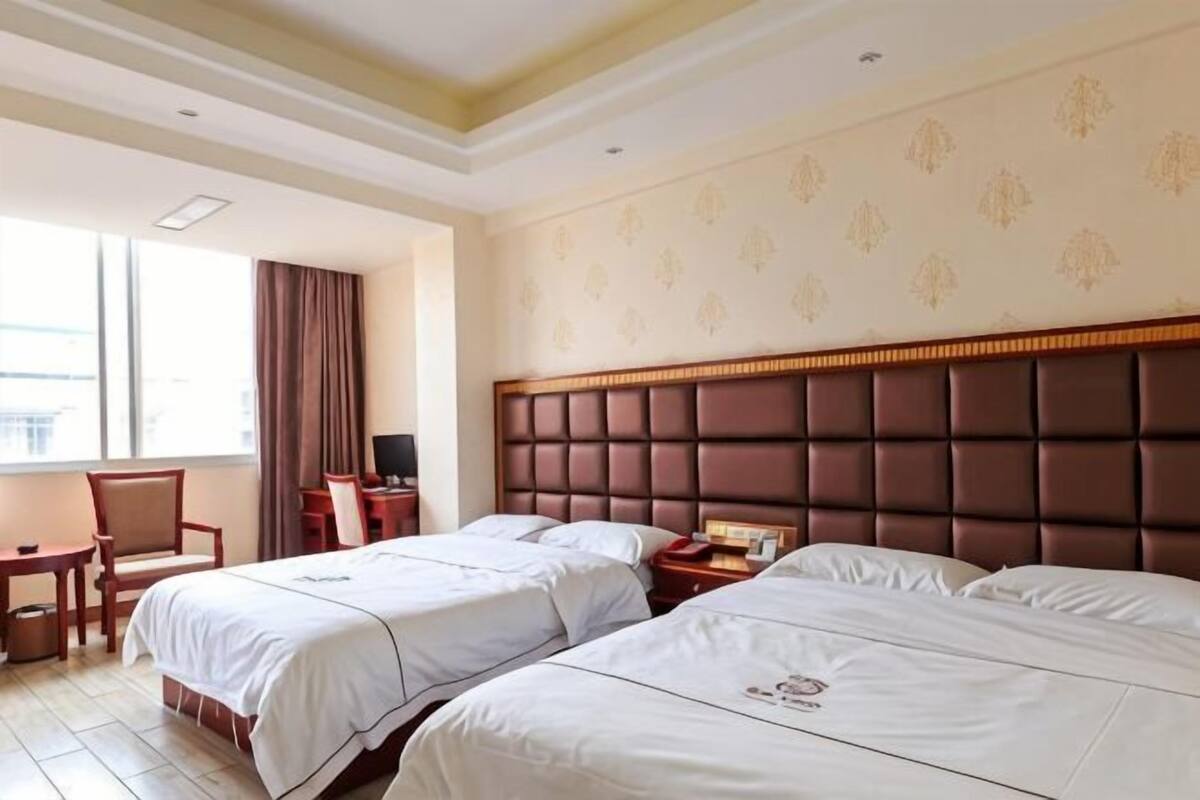 Une chambre d’hôtel avec deux lits, un bureau et une chaise.