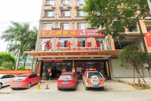 A hotel with a red sign, multiple cars parked in front, and a tree beside the entrance. - Tyrone Le Grand Large Hotel (Cenxi)