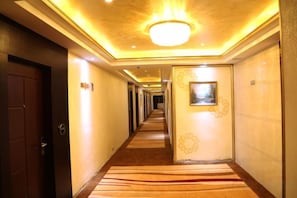 A hotel corridor with a carpeted floor, a door on the left, and a framed picture on the right wall. - Tyrone Le Grand Large Hotel (Cenxi)