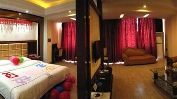 A hotel room with a bed, a sofa, a TV, and a table with a lamp.