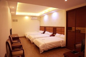 Habitación de hotel con tres camas, un escritorio y una silla.