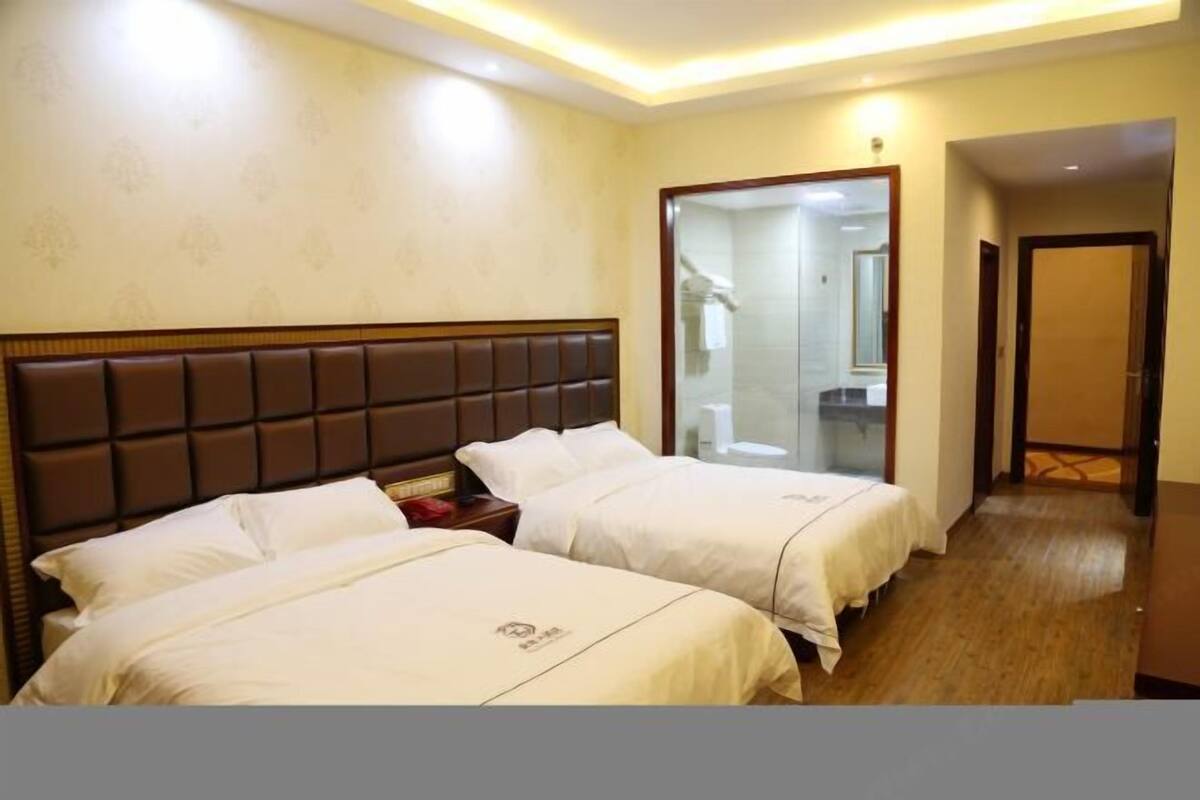 Une chambre d’hôtel avec deux lits, un grand miroir et un plancher en bois.