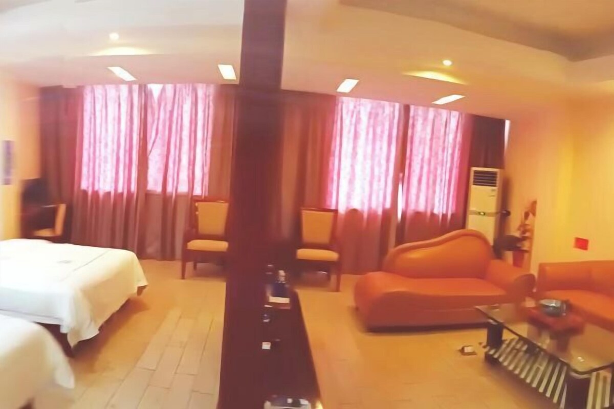 A hotel room with a bed, a sofa, a coffee table, and a TV.