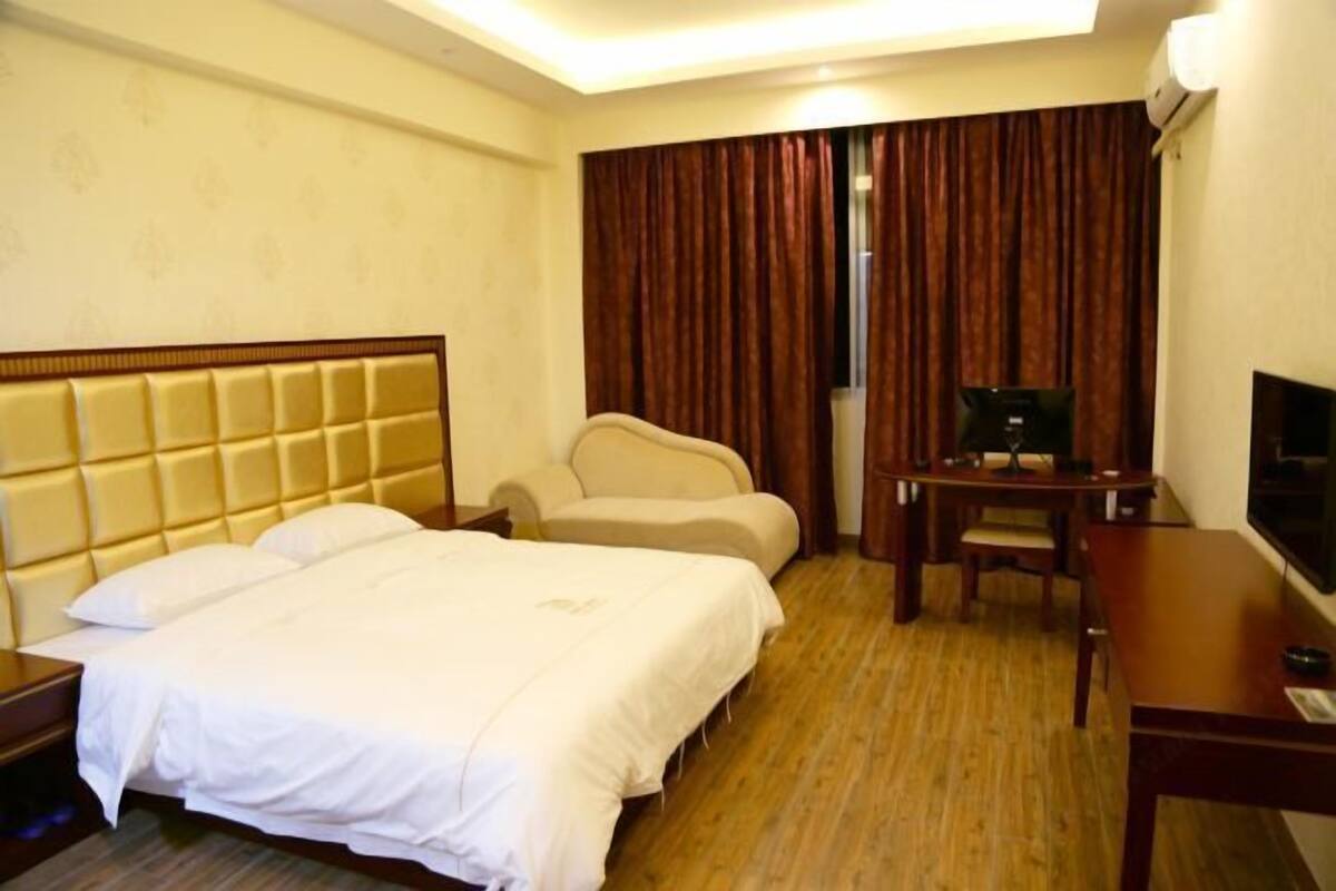 Une chambre d’hôtel avec un lit, un bureau, une chaise et un téléviseur.