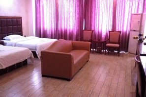 Habitación de hotel con dos camas, un sofá, una mesita y una silla.