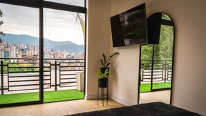 Ein modernes Schlafzimmer mit großem Fenster, einem an der Wand befestigten Flachbildfernseher und einem Blumentopf.
