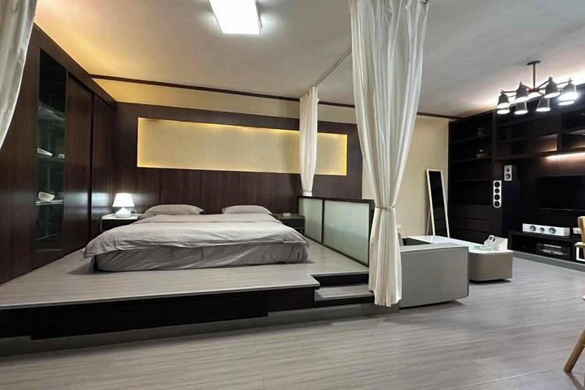 A modern bedroom with a bed, bedside tables, and a built-in TV.