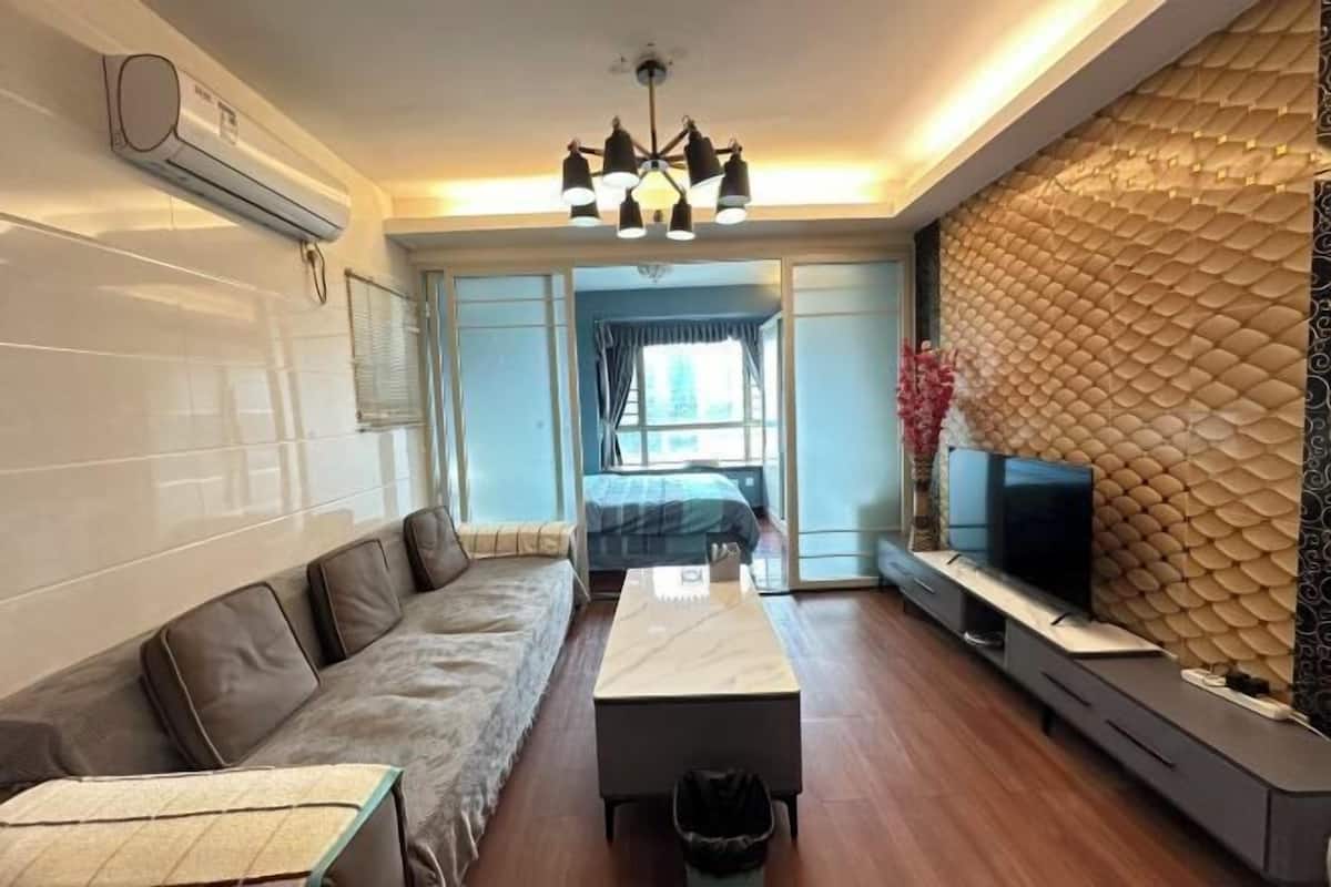 A modern living room with a sofa, a coffee table, a TV, and a wall-mounted air conditioner.
