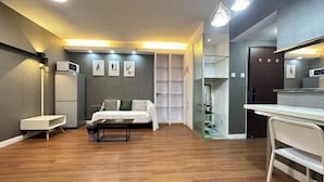 A modern hotel room with a bed, a desk, a chair, and a wardrobe.