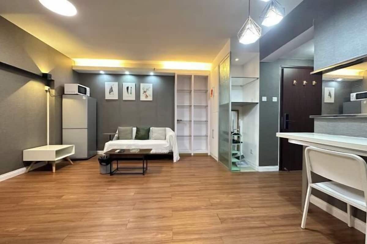 A modern hotel room with a bed, a desk, a chair, and a wardrobe.