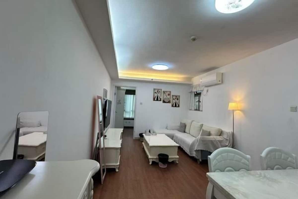 A modern, well-lit room with a bed, a desk, a chair, and a TV.